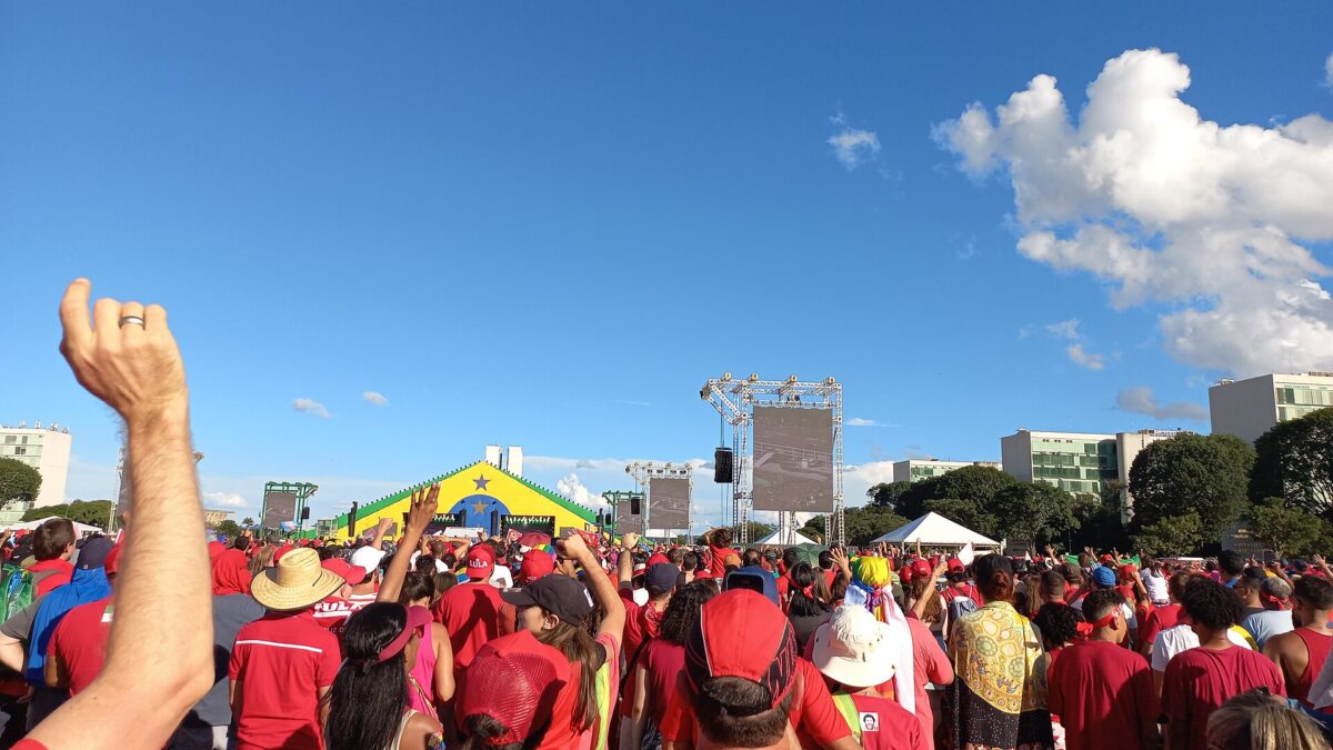 Multitud de simpatizantes de Lula con remeras rojas frente a un escenario con los colores de Brasil en Brasilia